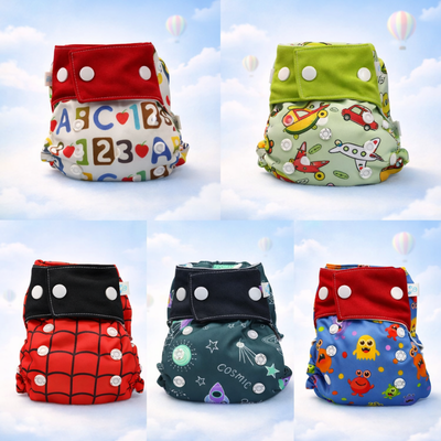 Cinco pañales de tela reutilizables de colores con cierres a presión sobre un fondo de cielo nublado.