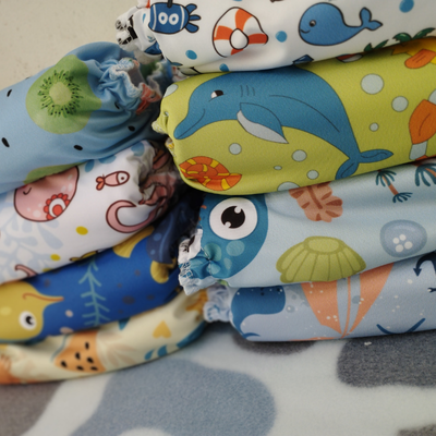 Pila de pañales de tela de colores con diseños de océano y frutas.