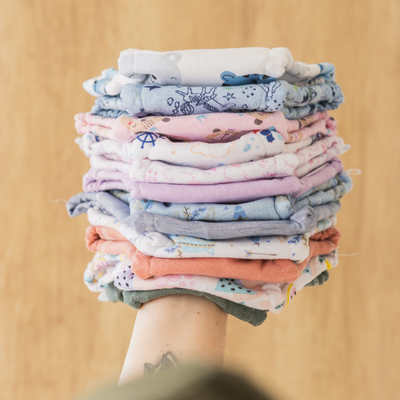 Mano sosteniendo una pila alta de telas de colores dobladas.