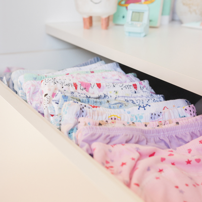 Cajón con ropa interior infantil colorida y con varios estampados, organizada de forma ordenada en un cajón blanco.