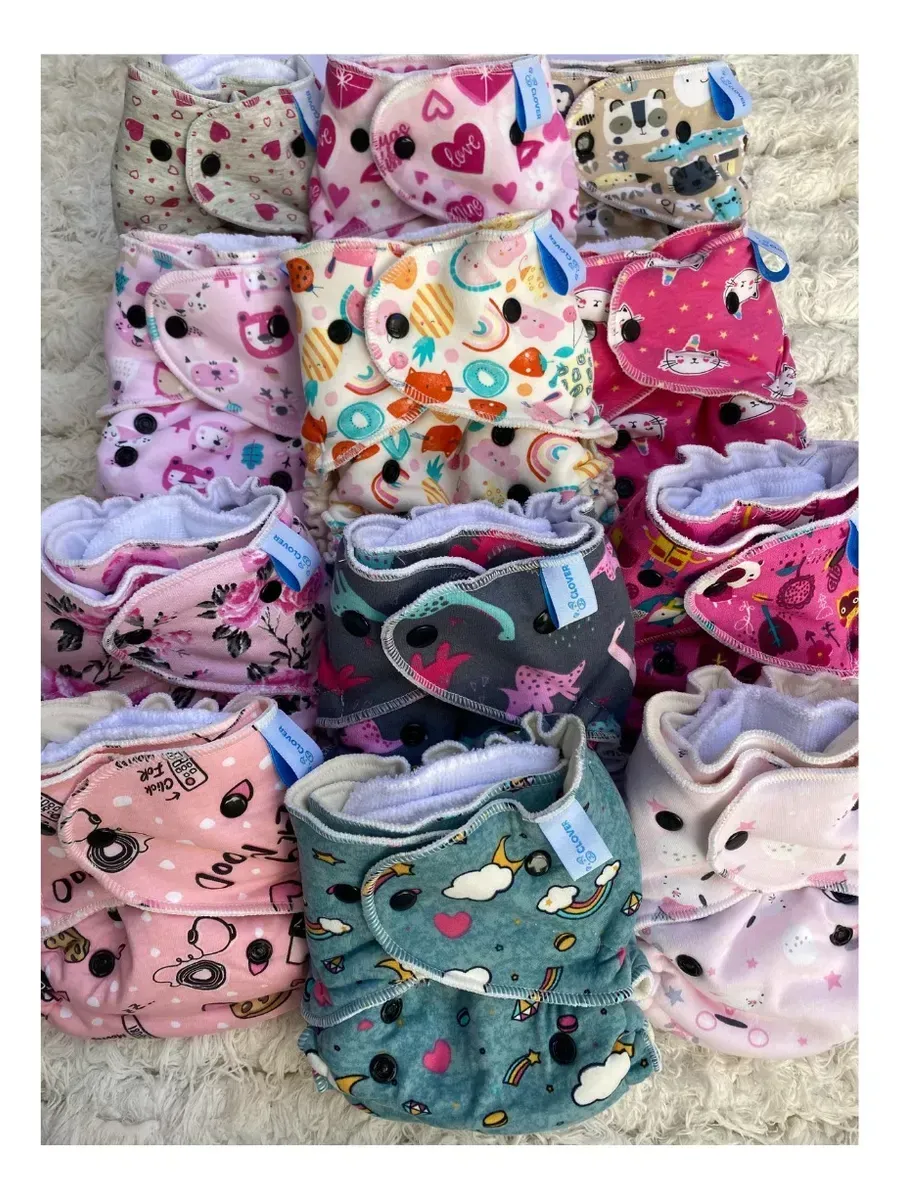 Pilas de pañales de tela de colores sobre un cambiador de madera clara en una guardería.