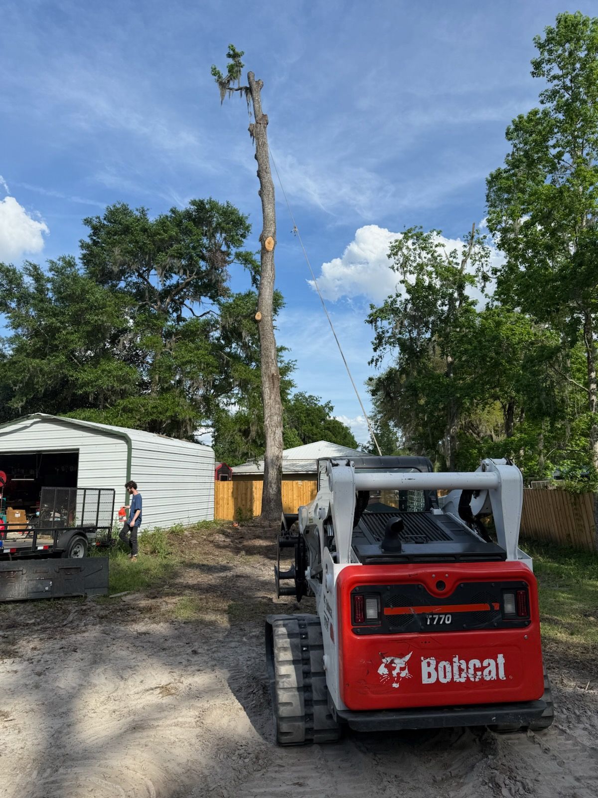 A man is sitting on top of a bucket truck in front of a house.