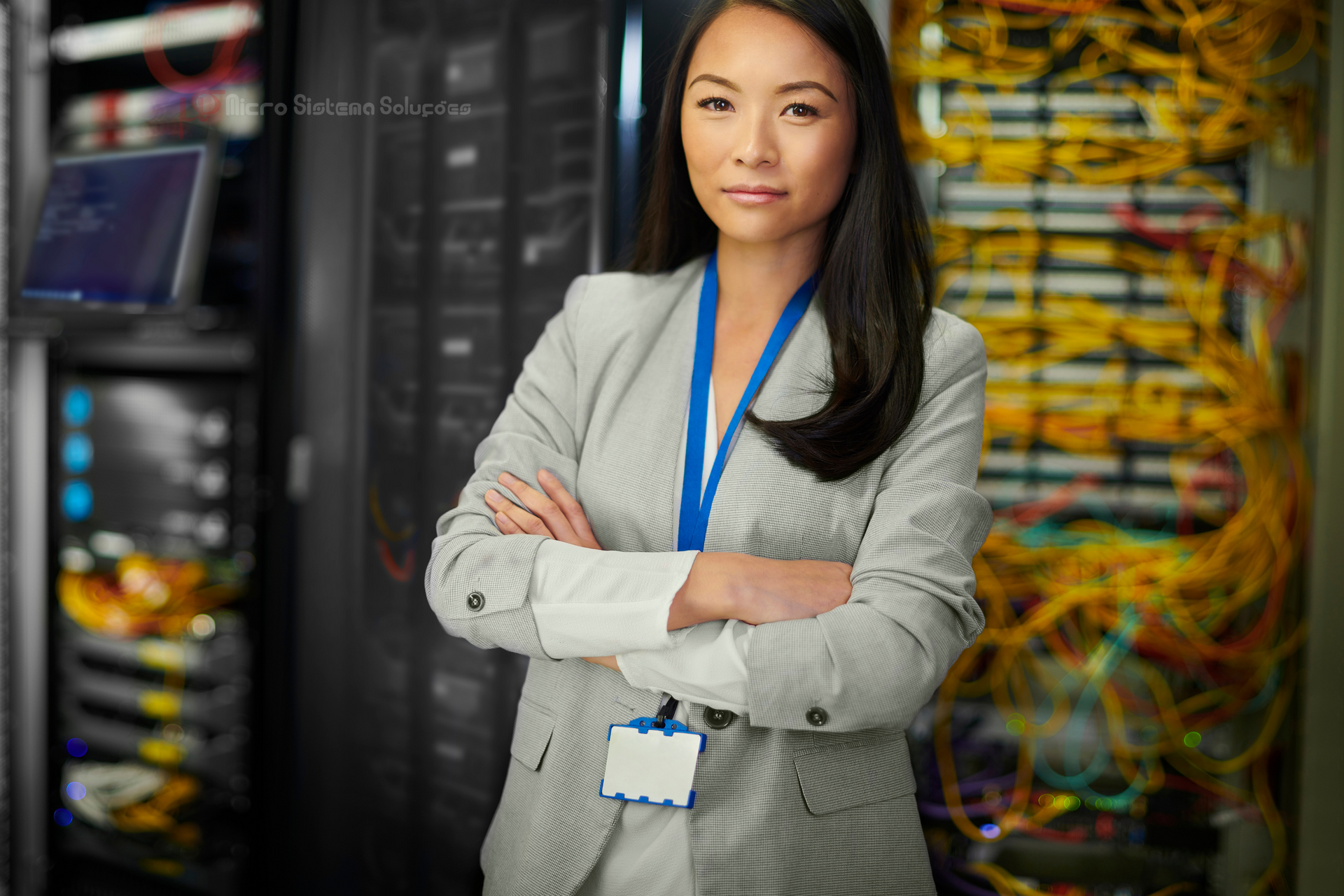 A woman is standing in a server room with her arms crossed.