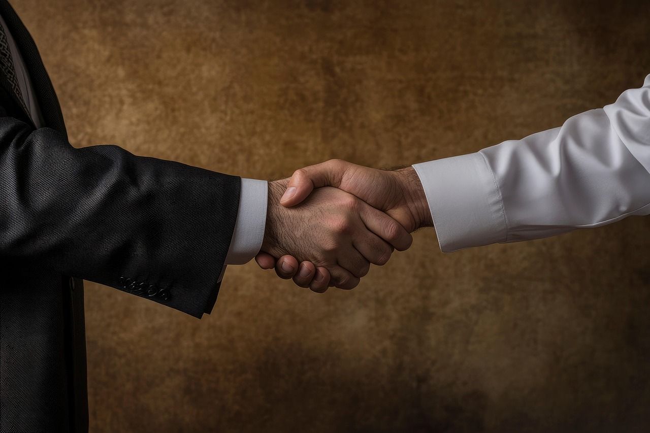 A man in a suit and a man in a white shirt are shaking hands.