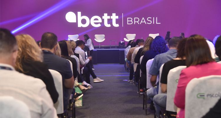 A group of people are sitting in chairs in front of a sign that says bett brasil.