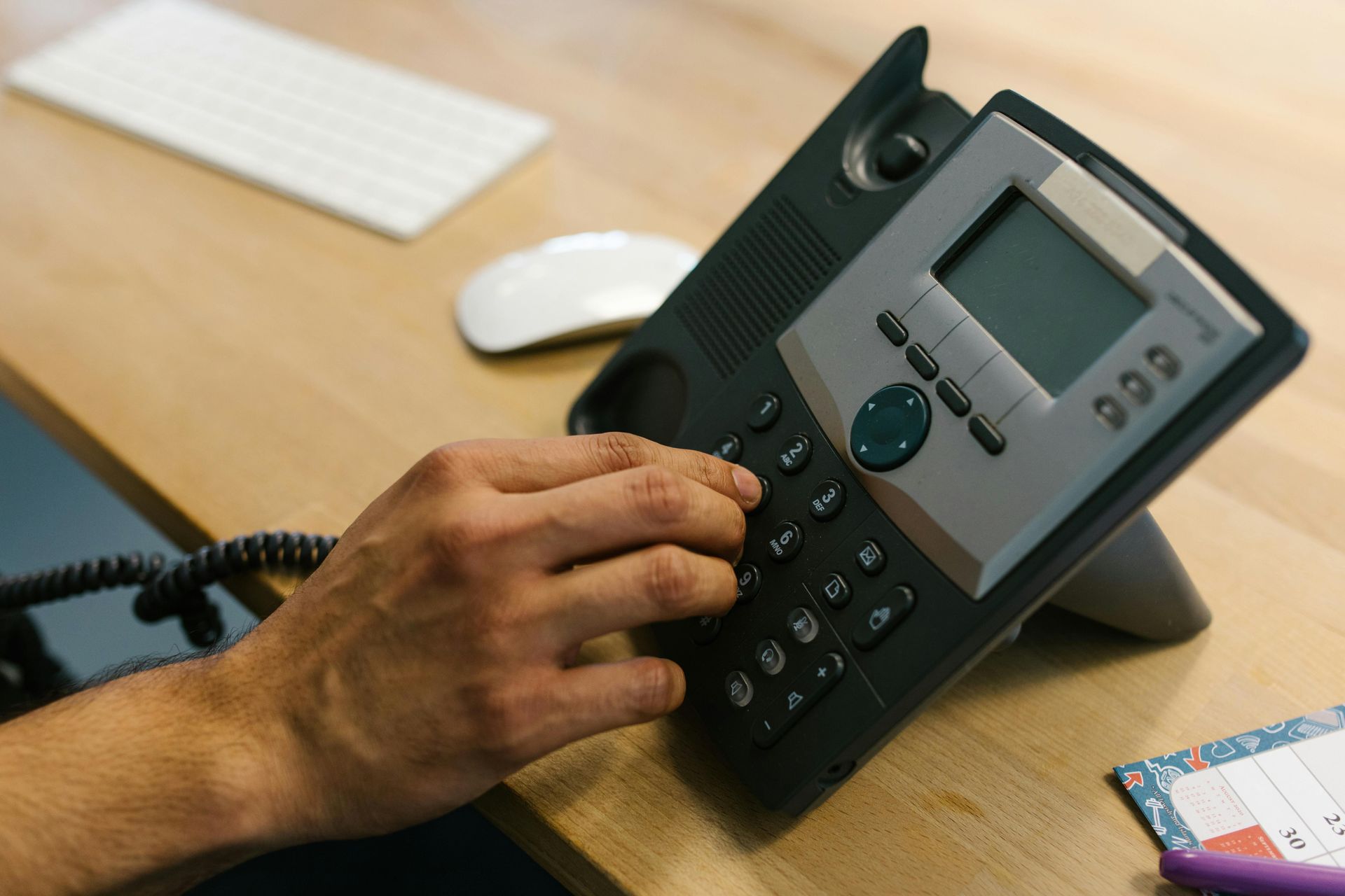 Uma pessoa está usando um telefone em uma mesa de madeira.