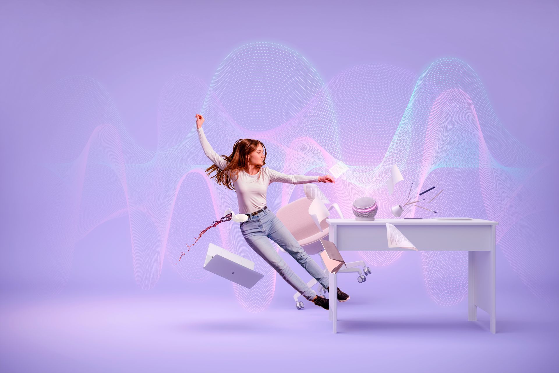 A woman is jumping in the air in front of a desk.