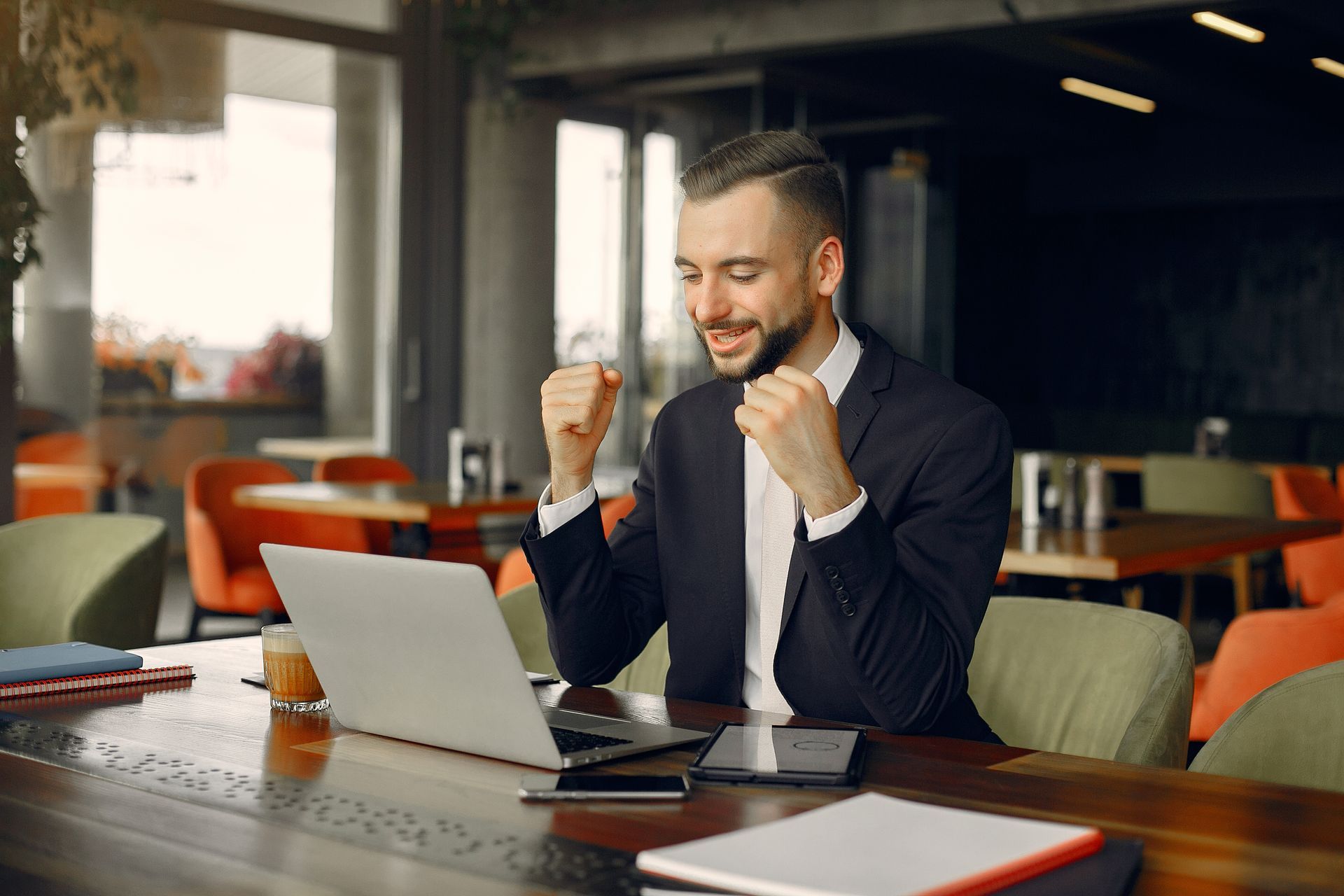 A man in a suit is sitting at a table with a laptop computer.