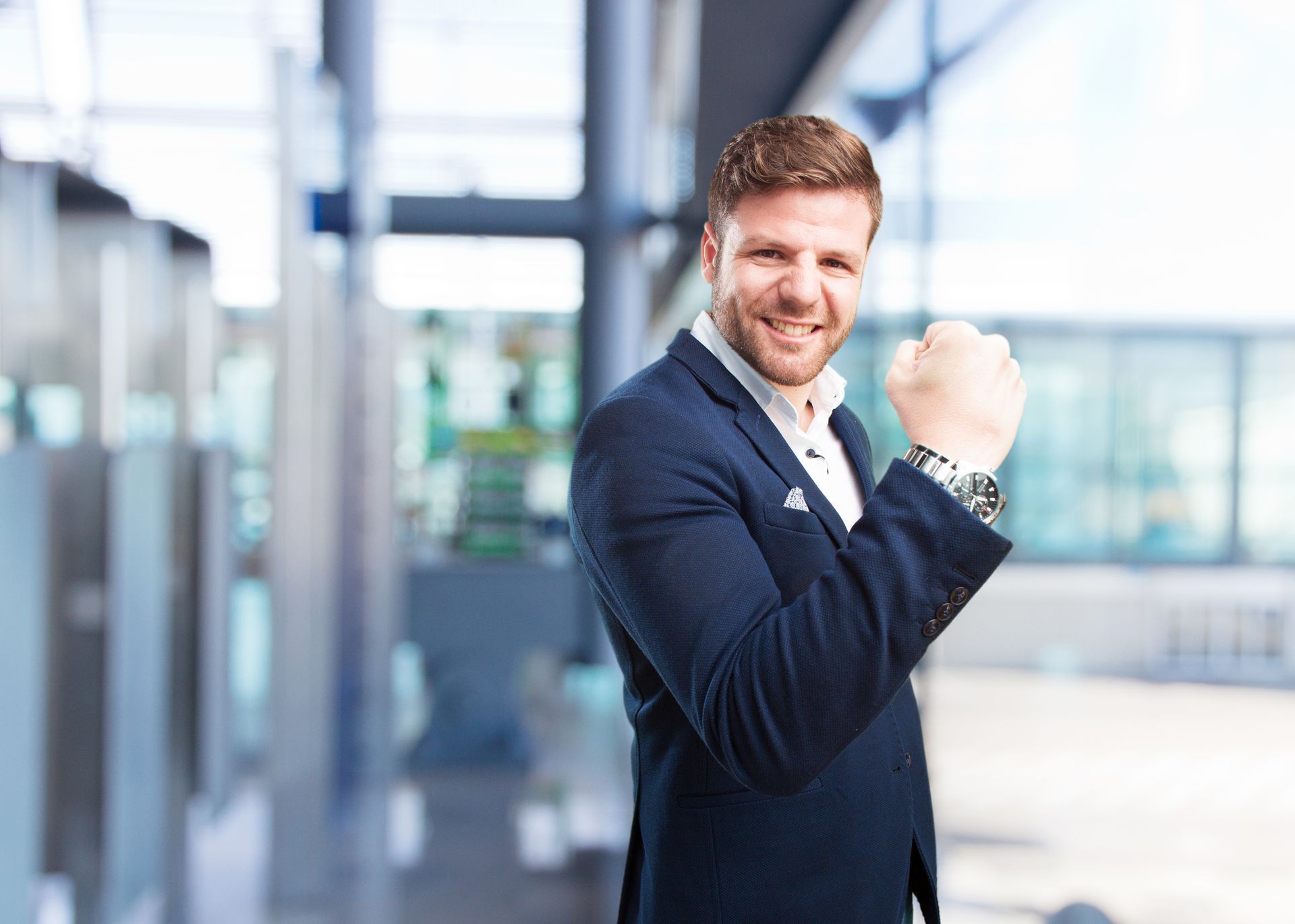 A man in a suit is standing in an office with his fist in the air.