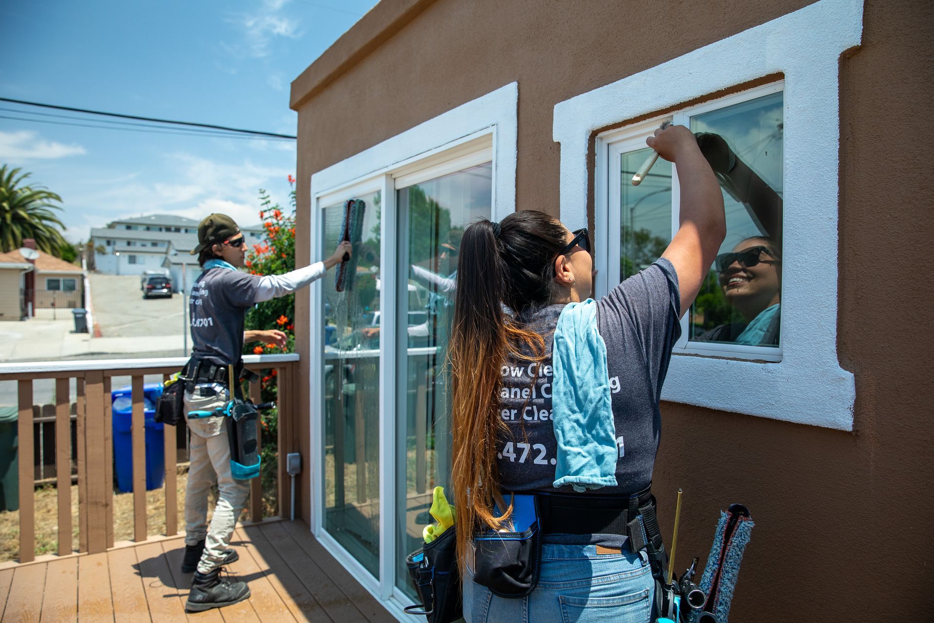 A man and a woman are cleaning a window on a house.