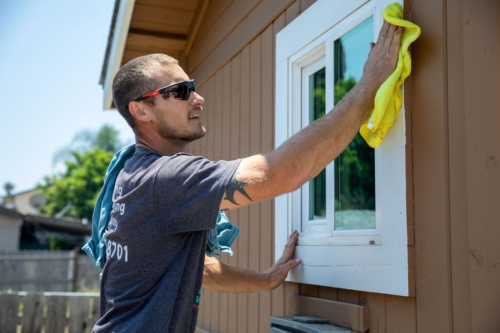 A man is cleaning a window with a yellow cloth.