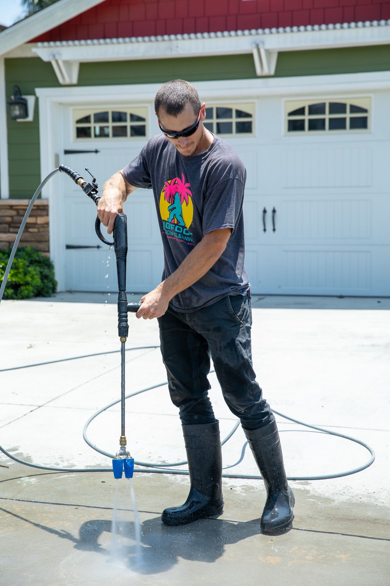 A man is using a high pressure washer to clean a driveway.