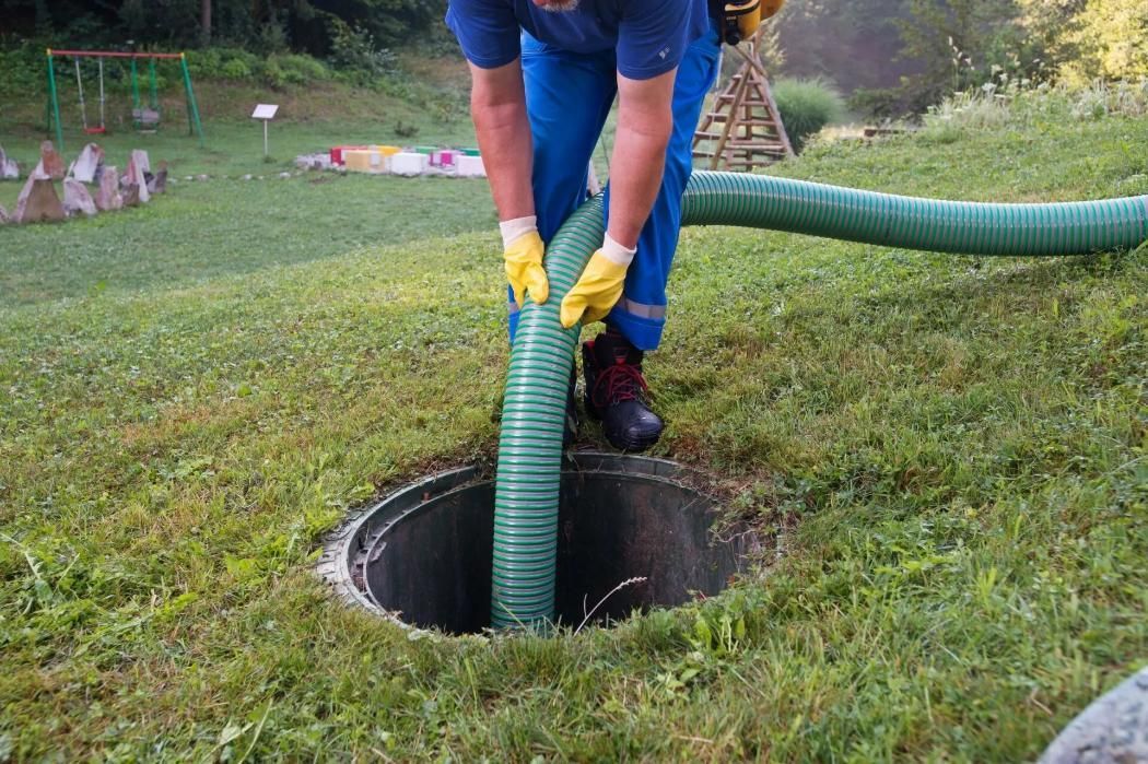 A Man is Pumping Water Into a Septic Tank With a Green Hose — Mid Coast Liquid Waste In Coomba Park, NSW