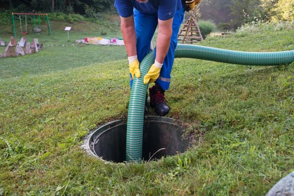 A Worker Inserts a Green Hose Into an Open Septic Tank — Mid Coast Liquid Waste In Rainbow Flat, NSW