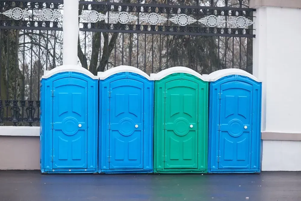 A Row of Blue and Green Portable Toilets Are Lined Up in Front of a Fence — Mid Coast Liquid Waste In Rainbow Flat, NSW