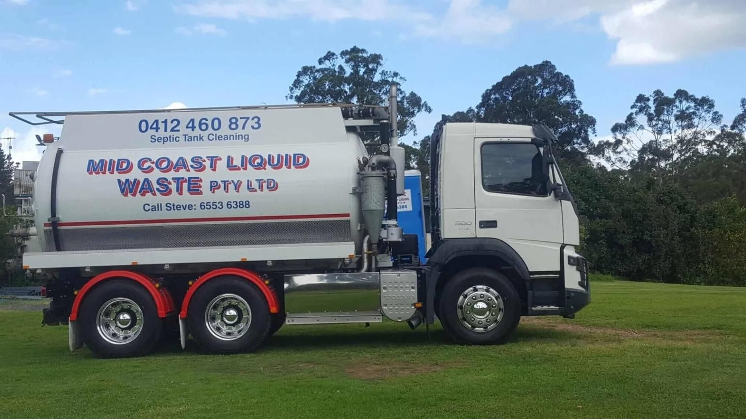 A White Waste Truck is Parked in a Grassy Field — Mid Coast Liquid Waste In Nabiac, NSW