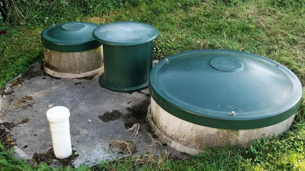 A Septic Tank With Three Green Lids and a White Pipe in the Grass — Mid Coast Liquid Waste In Rainbow Flat, NSW