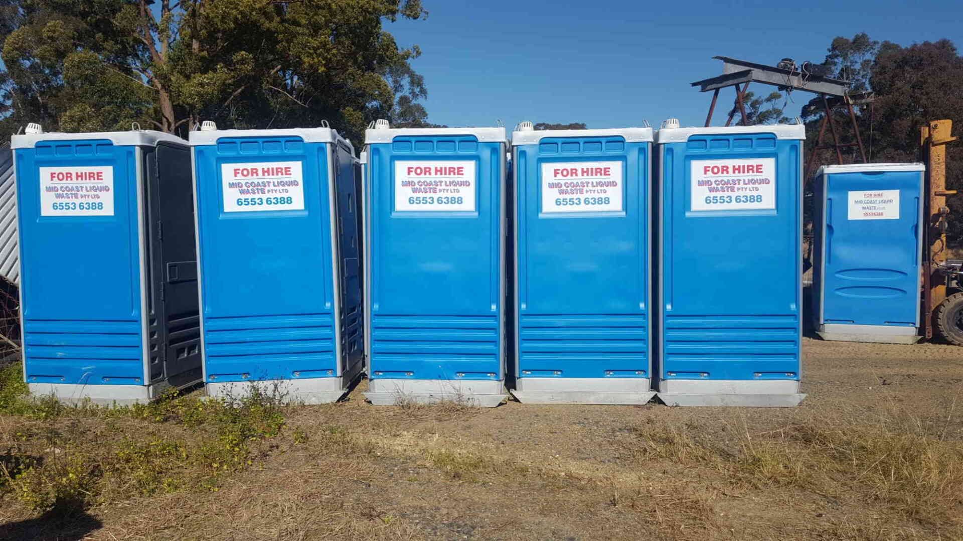 A Row of Blue Portable Toilets Are Lined Up in a Field — Mid Coast Liquid Waste In Nabiac, NSW