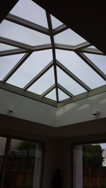 Skylight with geometric paneled design, cloudy sky visible. Two small security cameras are present.