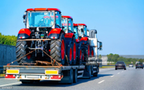 Heavy-duty truck used for local equipment hauling with red farming tractors secured on trailer.