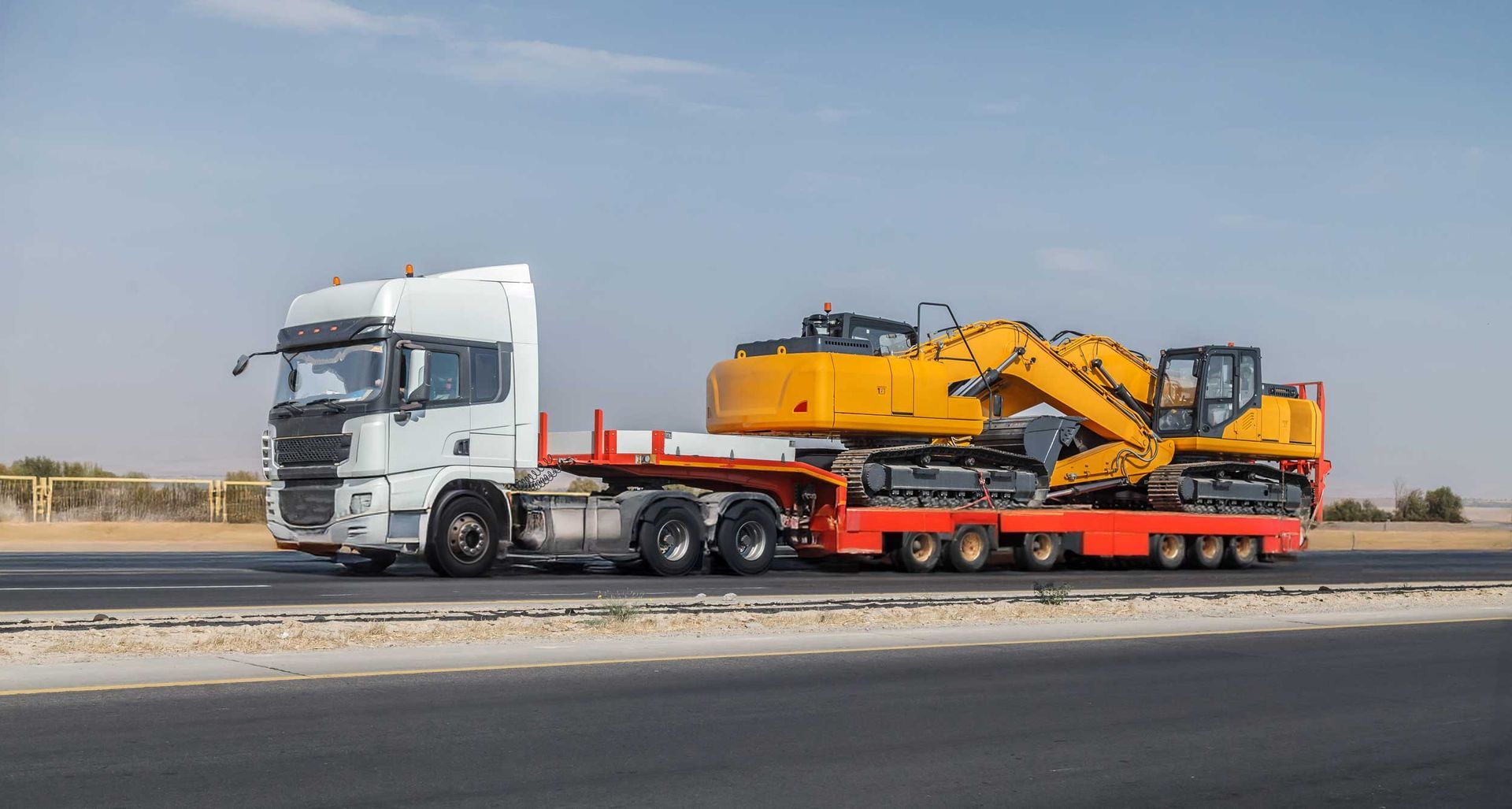 Semi truck transporting excavator on flatbed trailer for heavy equipment hauling.