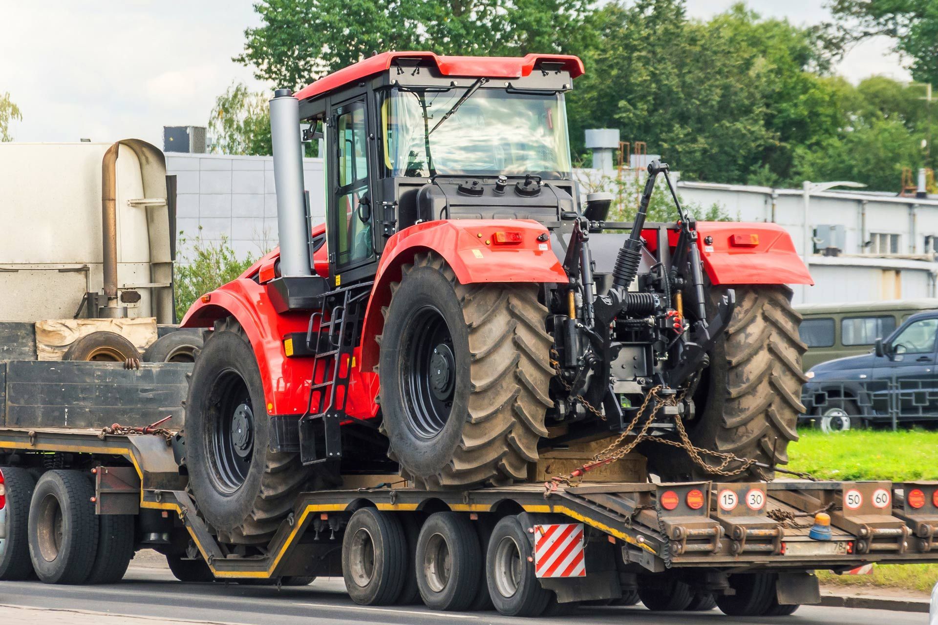Powerful red tractor on a platform trailer for road transportation