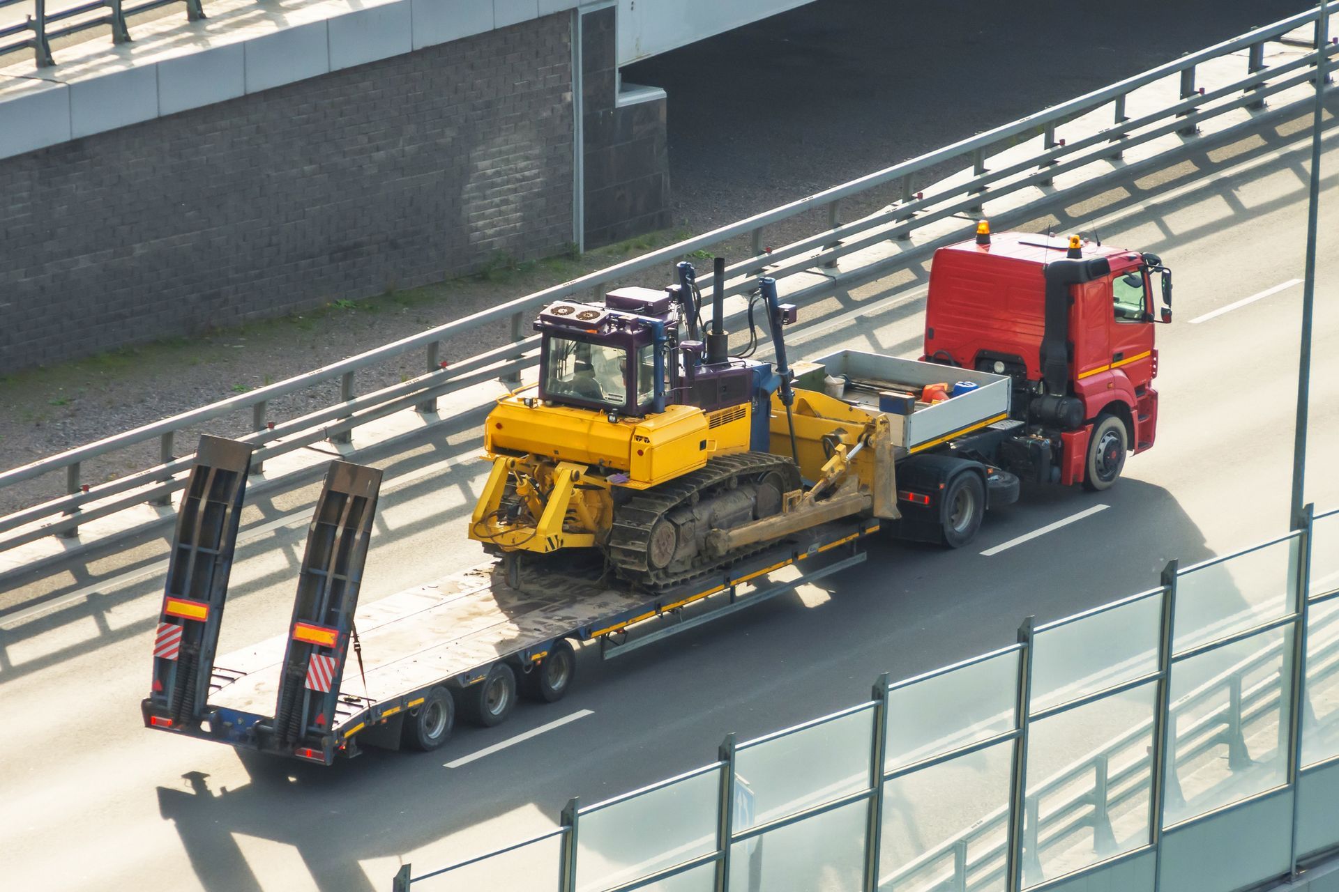 A long-bed truck transporting a bulldozer.
