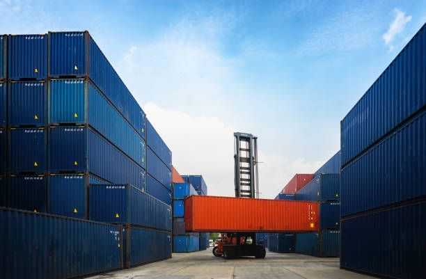 Crane lifting up container in yard.