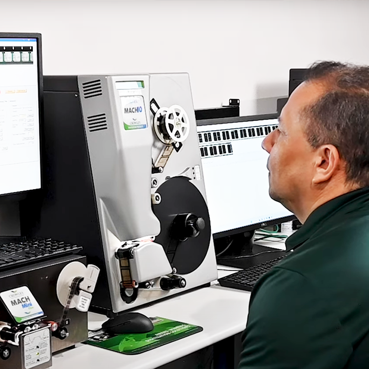 a man in a green shirt is sitting at a desk and using a microfilm scanner