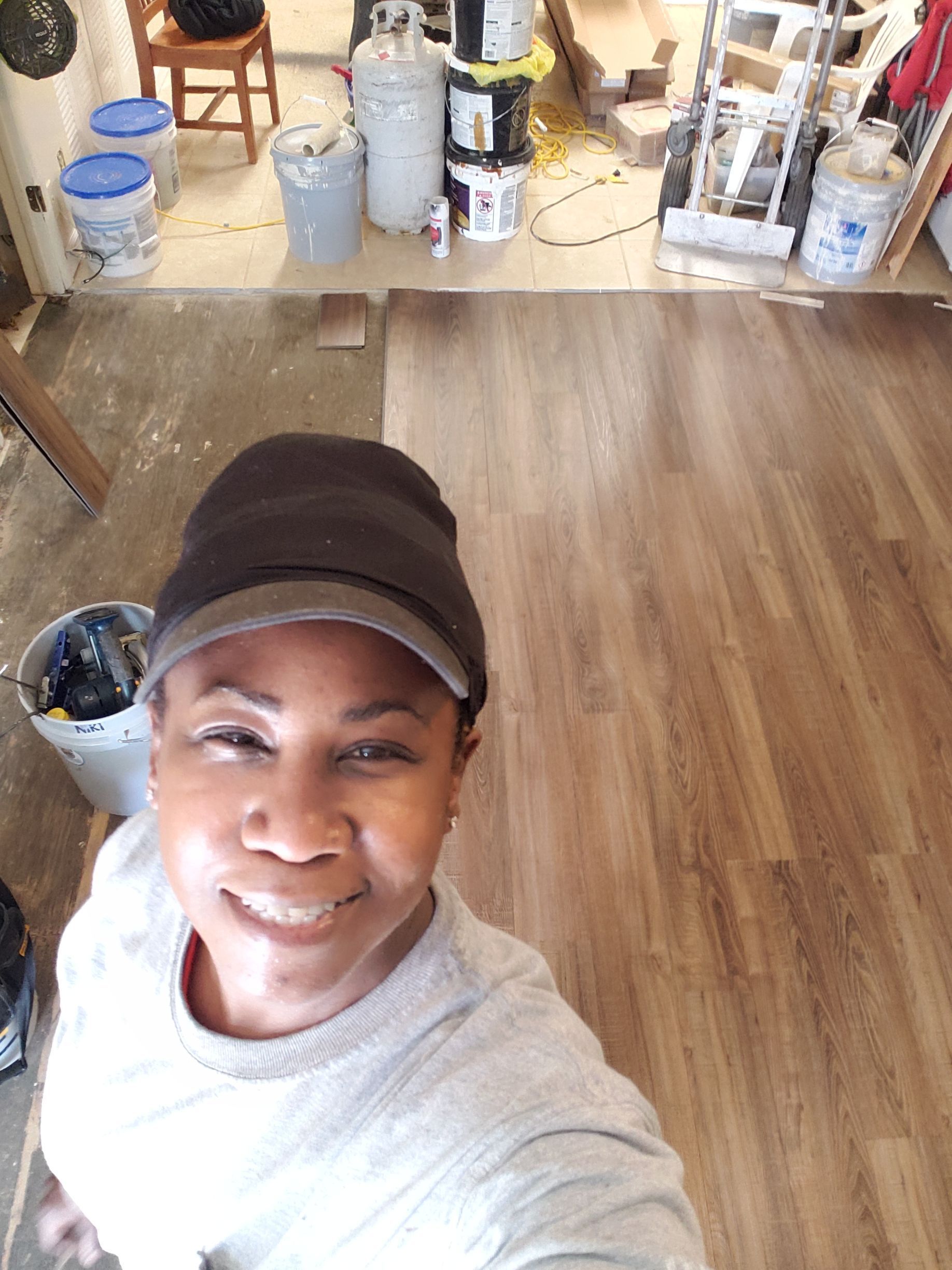 A woman is taking a selfie in a room with wooden floors.
