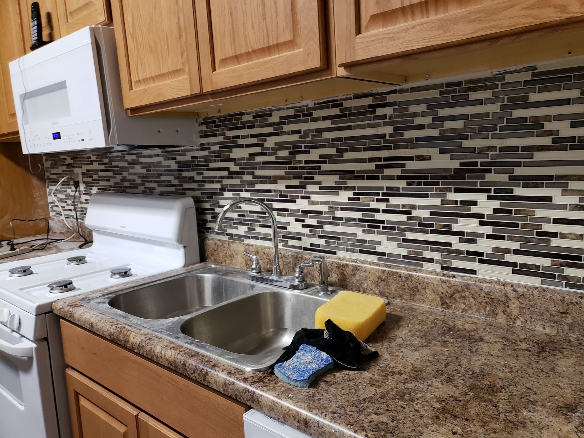 A kitchen with a sink , stove and microwave.