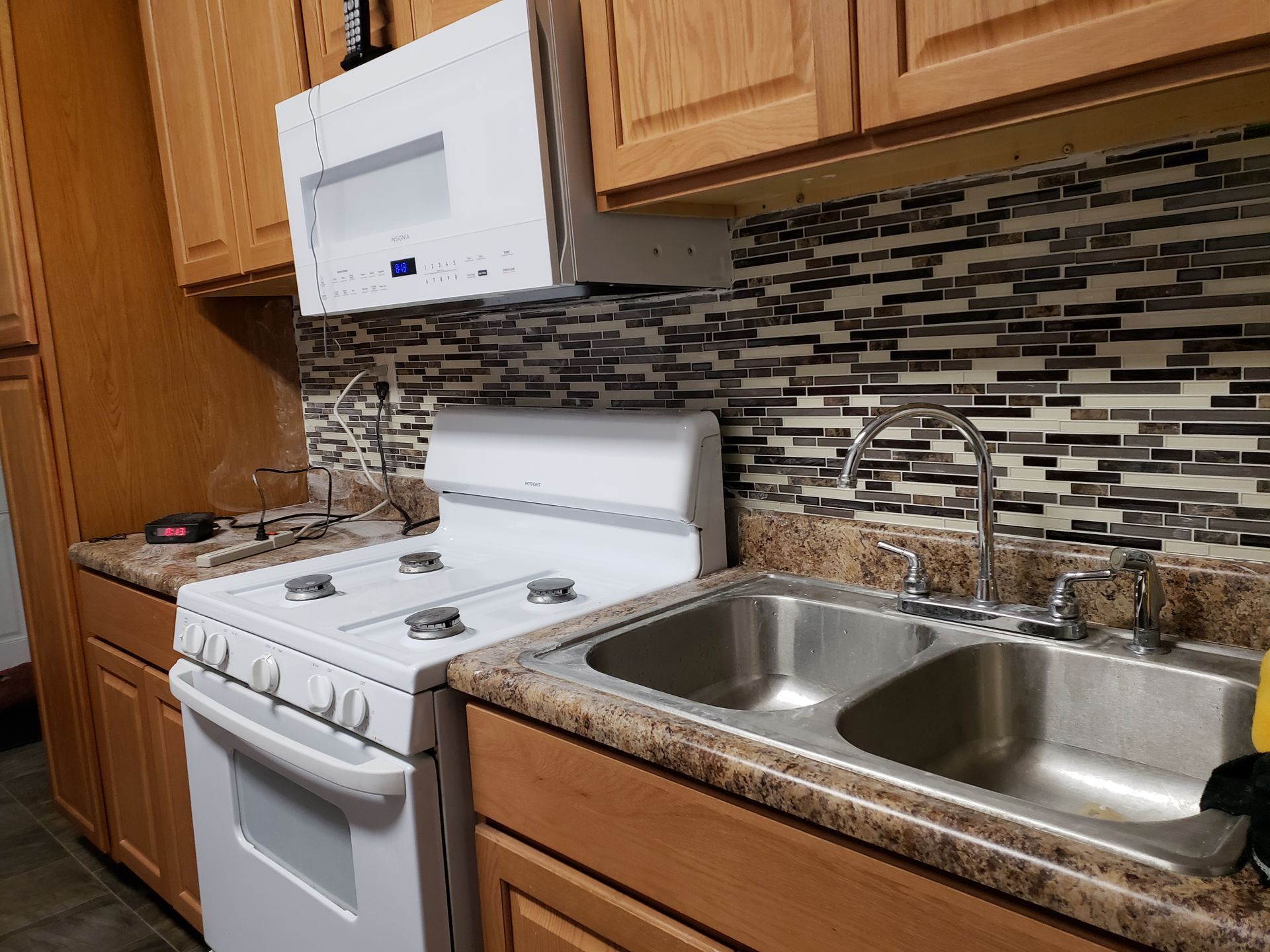 A kitchen with a stove , sink , and microwave.