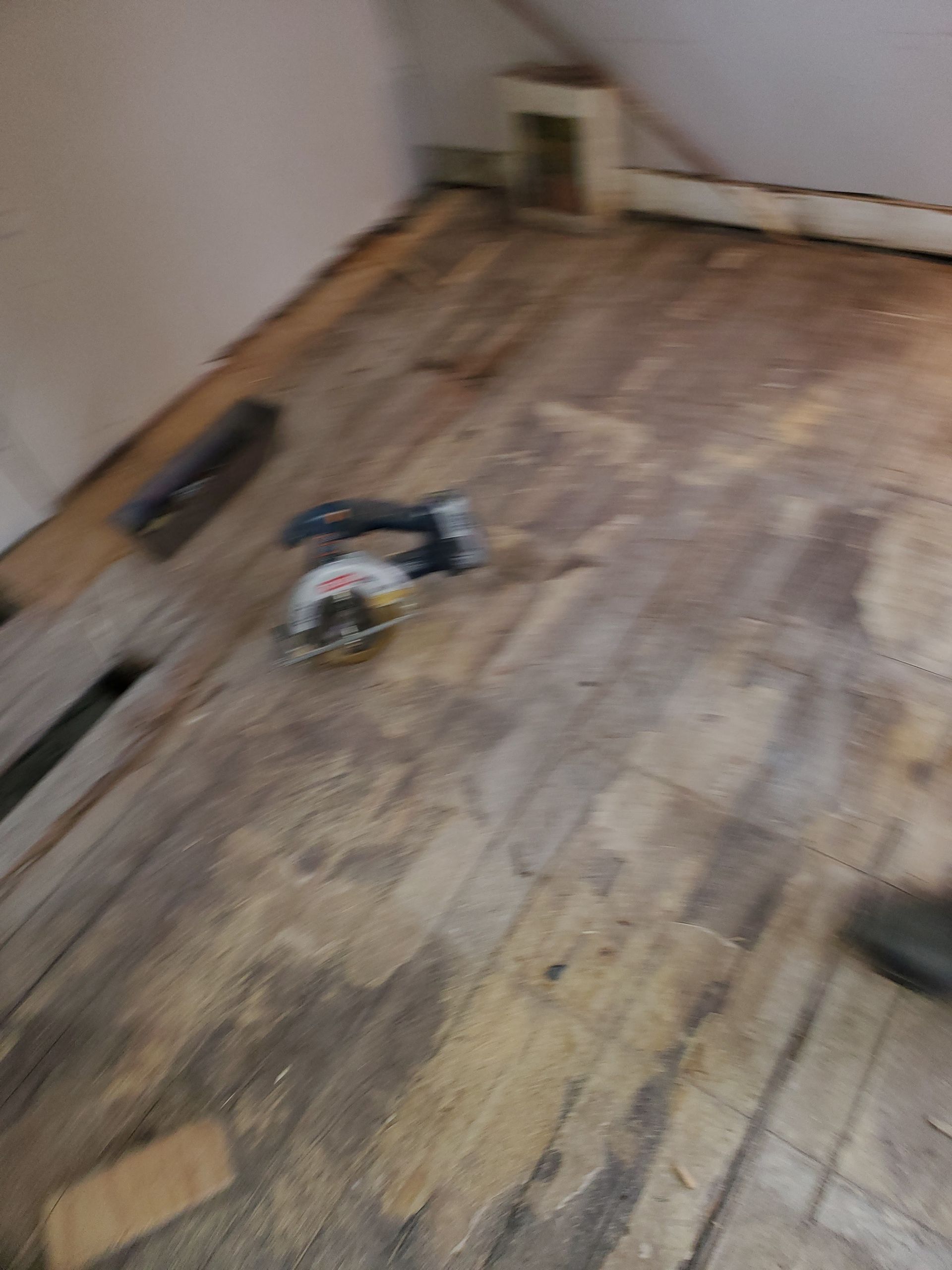 A circular saw is sitting on a wooden floor in a room.
