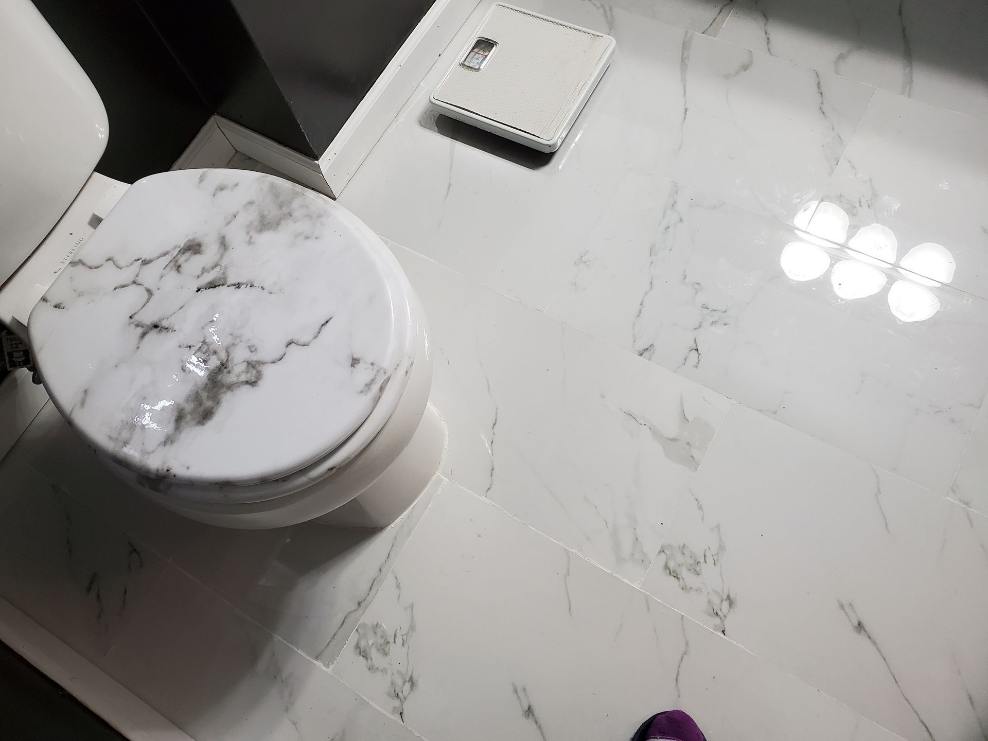 A white toilet with a marble seat in a bathroom.