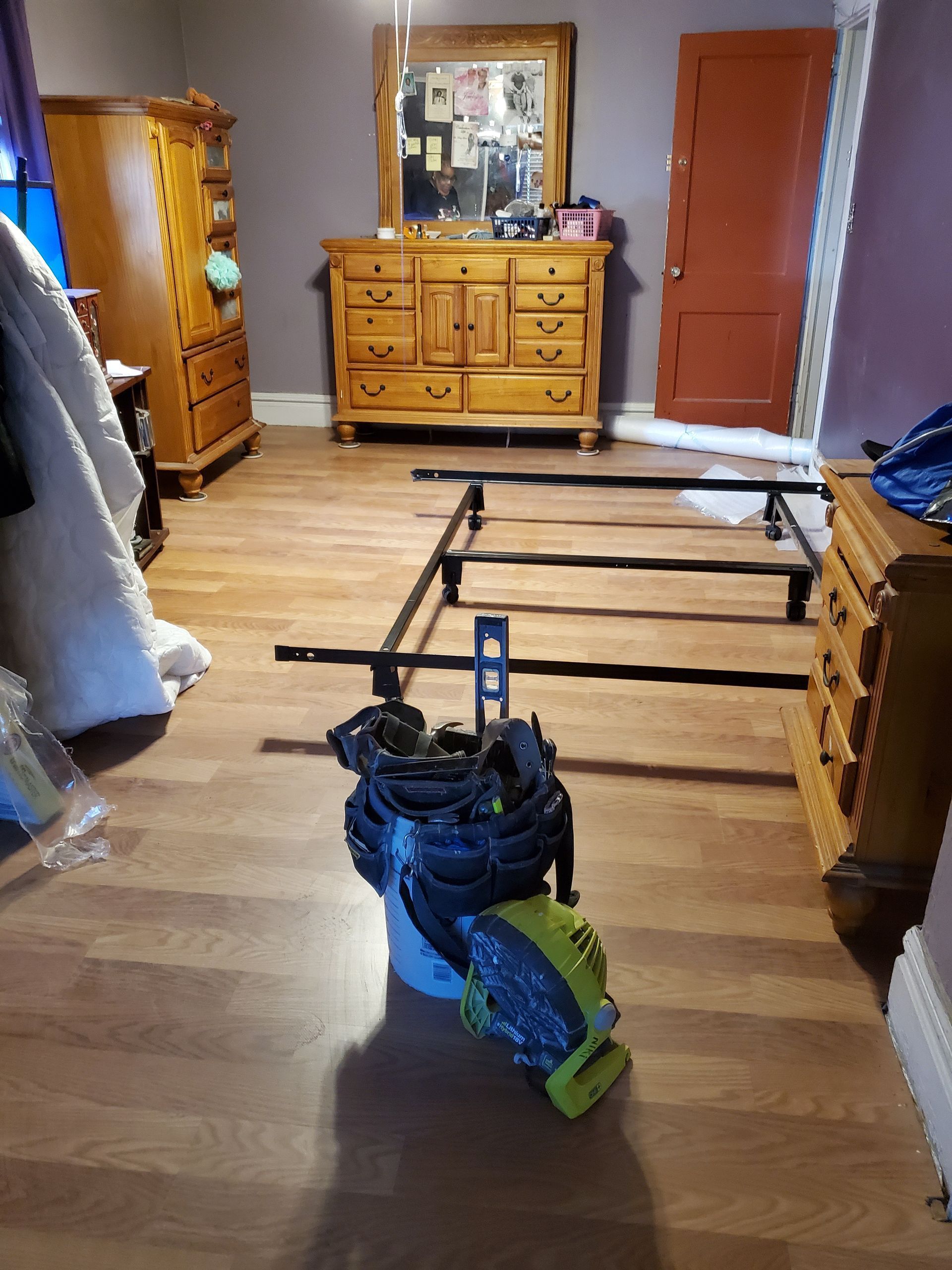 A bedroom with a bed frame , dresser , and mirror.
