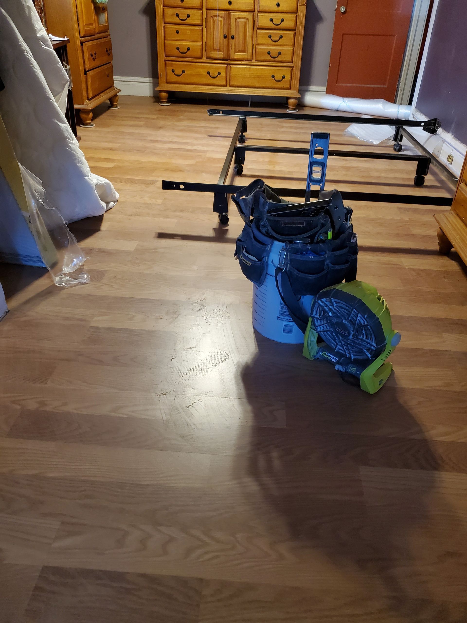 A bed frame is sitting on a wooden floor in a bedroom.