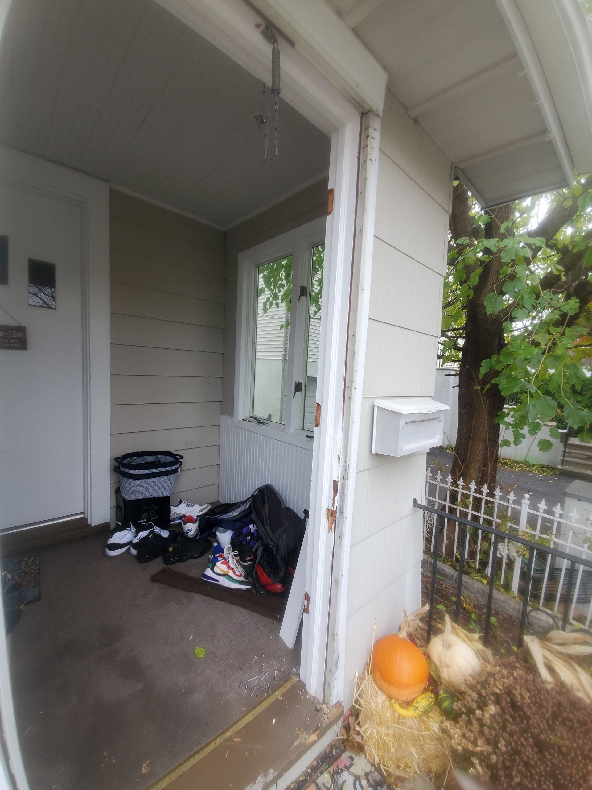 A doorway to a house with a mailbox and pumpkins on the ground.