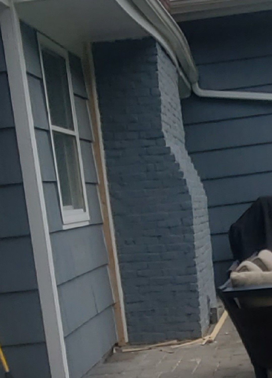 A blue house with a brick chimney on the side