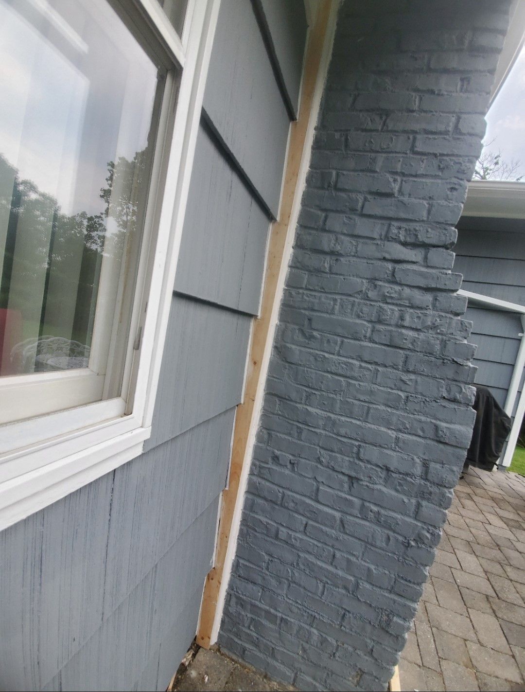 A brick wall with a window on the side of a house.