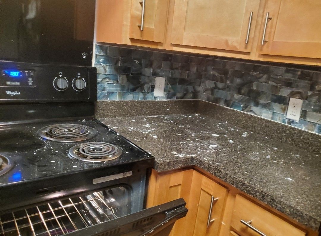 A kitchen with a stove top oven and a messy counter top.