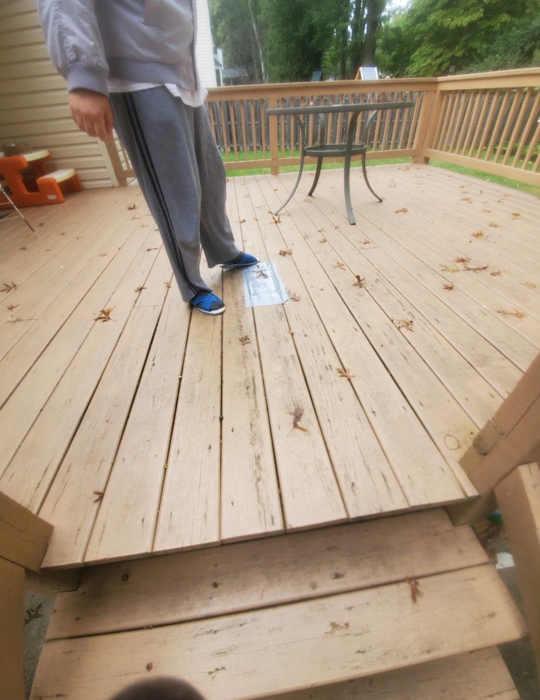 A person standing on a wooden deck with a table and chairs