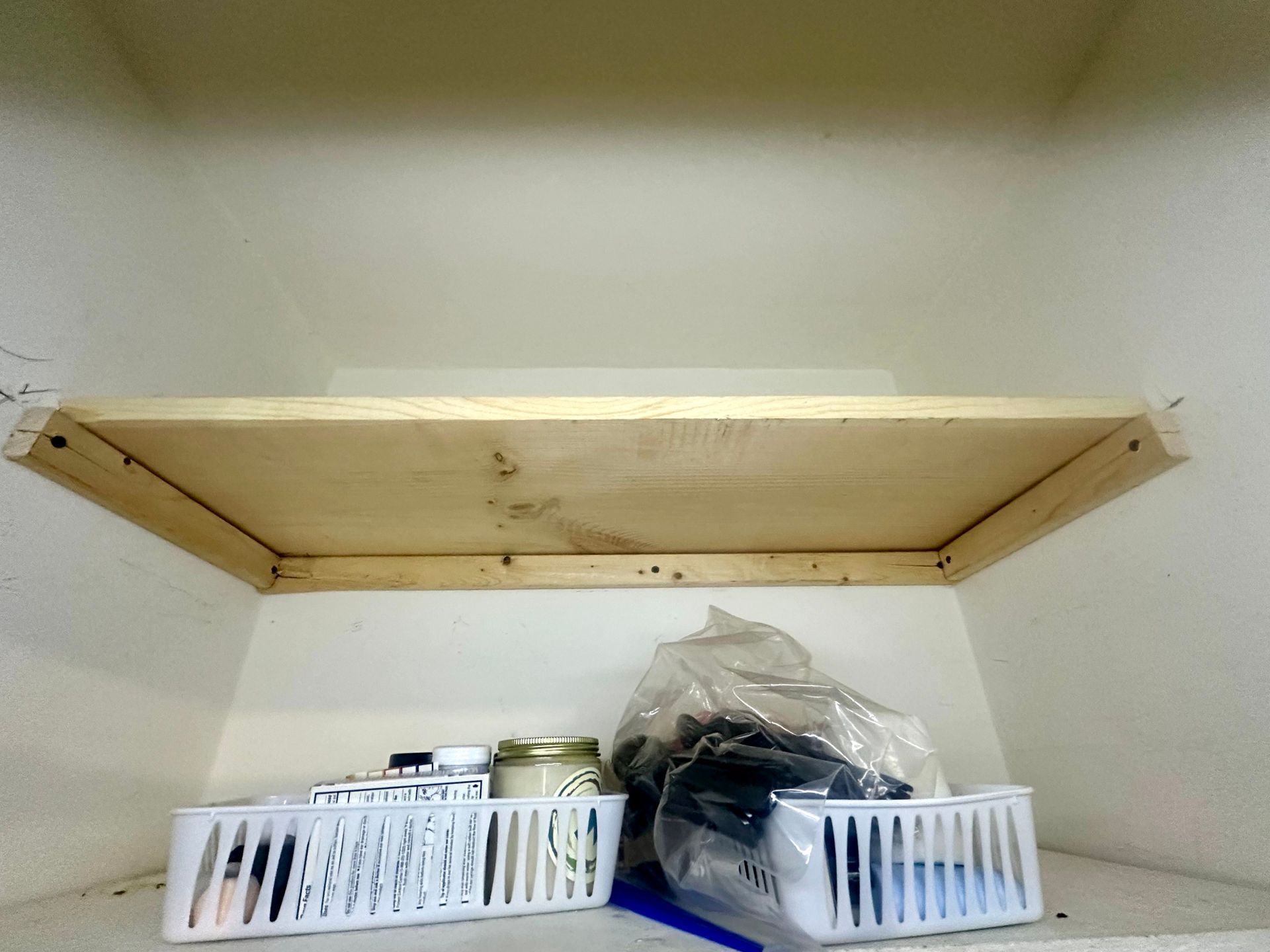 A wooden shelf with a plastic basket on it