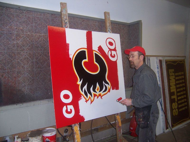 A man is painting a sign that says go on it