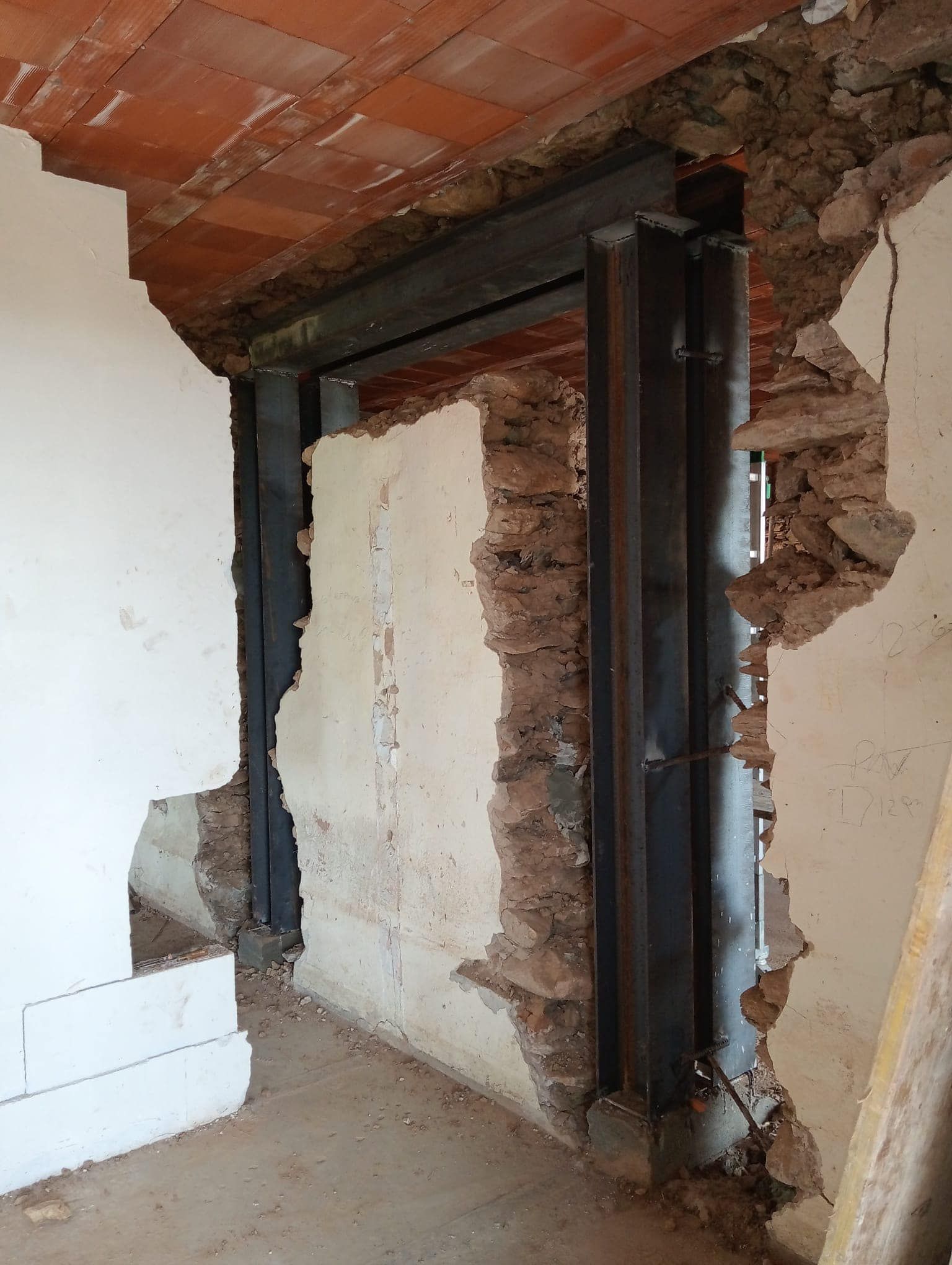 Un muro di mattoni attraversato da una trave di metallo.