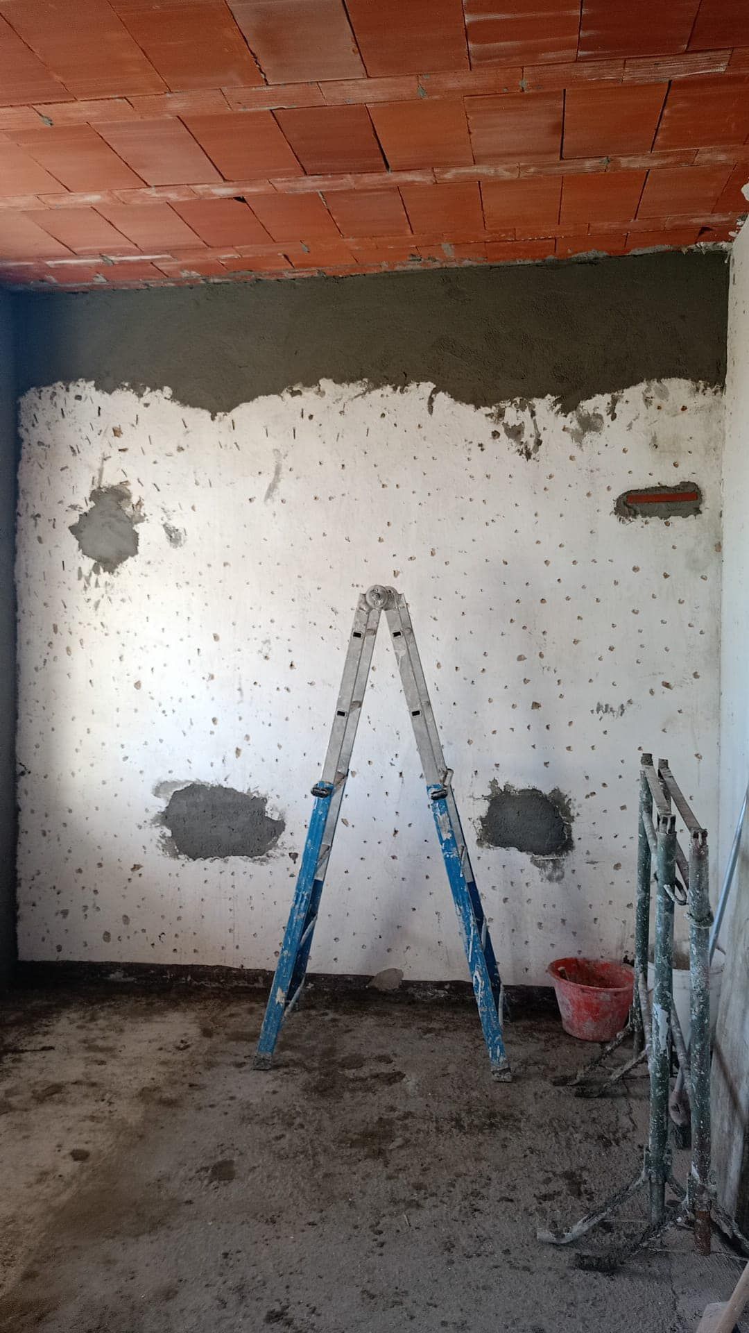 Una scala è appoggiata in una stanza con il soffitto in mattoni.