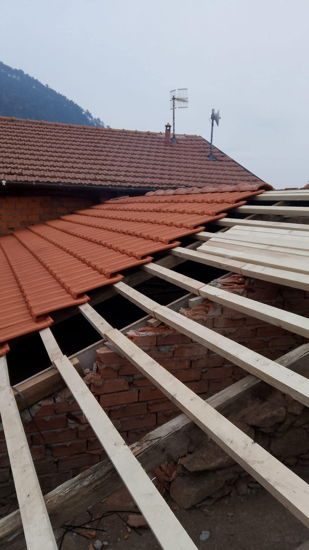 Si sta costruendo un tetto con tegole e travi di legno.