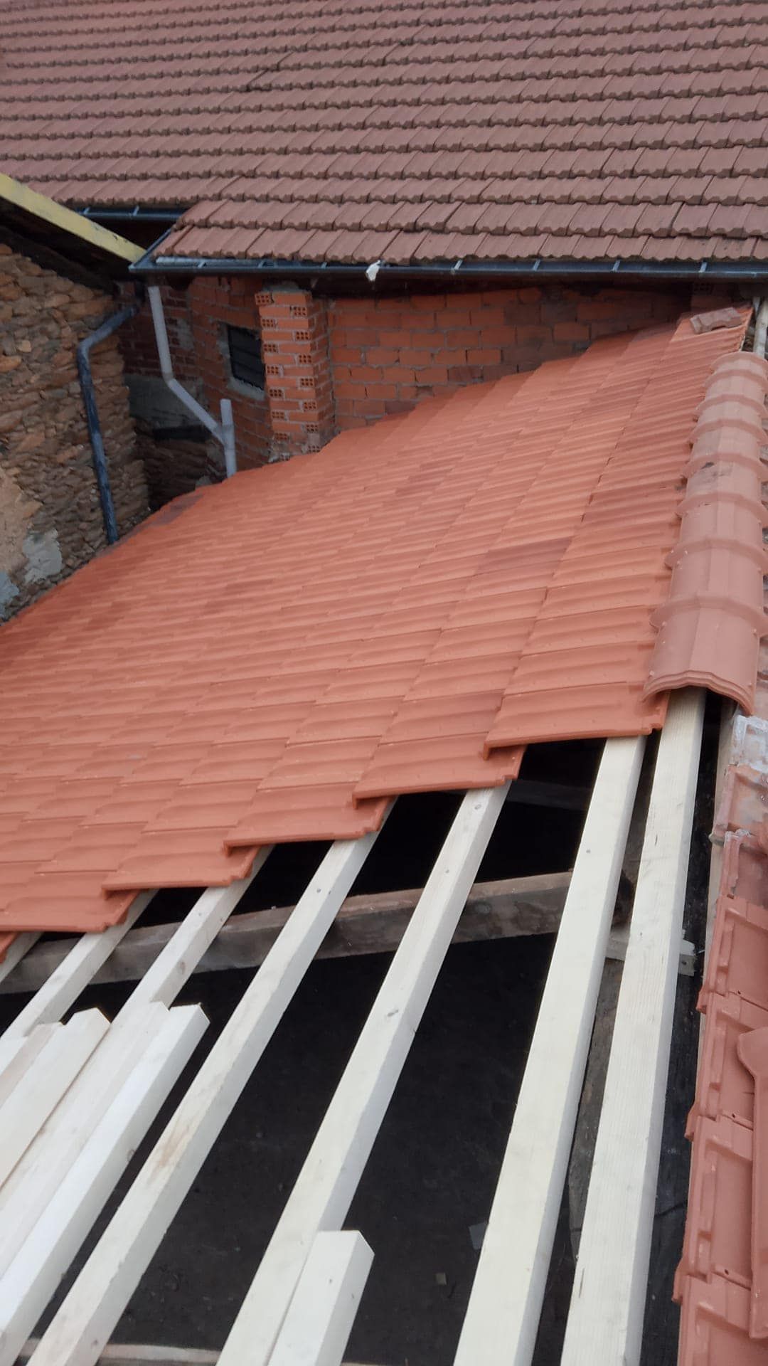 Un tetto di tegole rosse viene costruito sopra una struttura di legno.