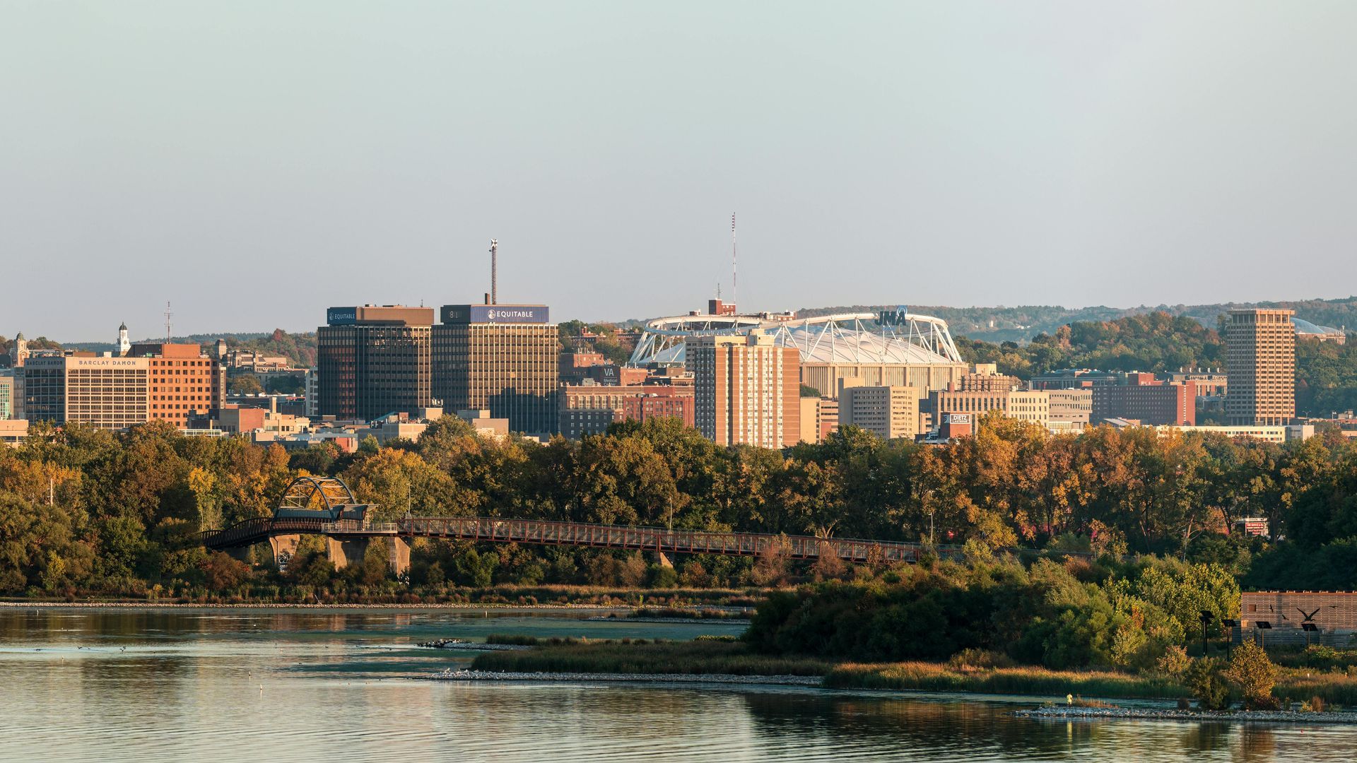 Skyline view of buildings, river and green trees.