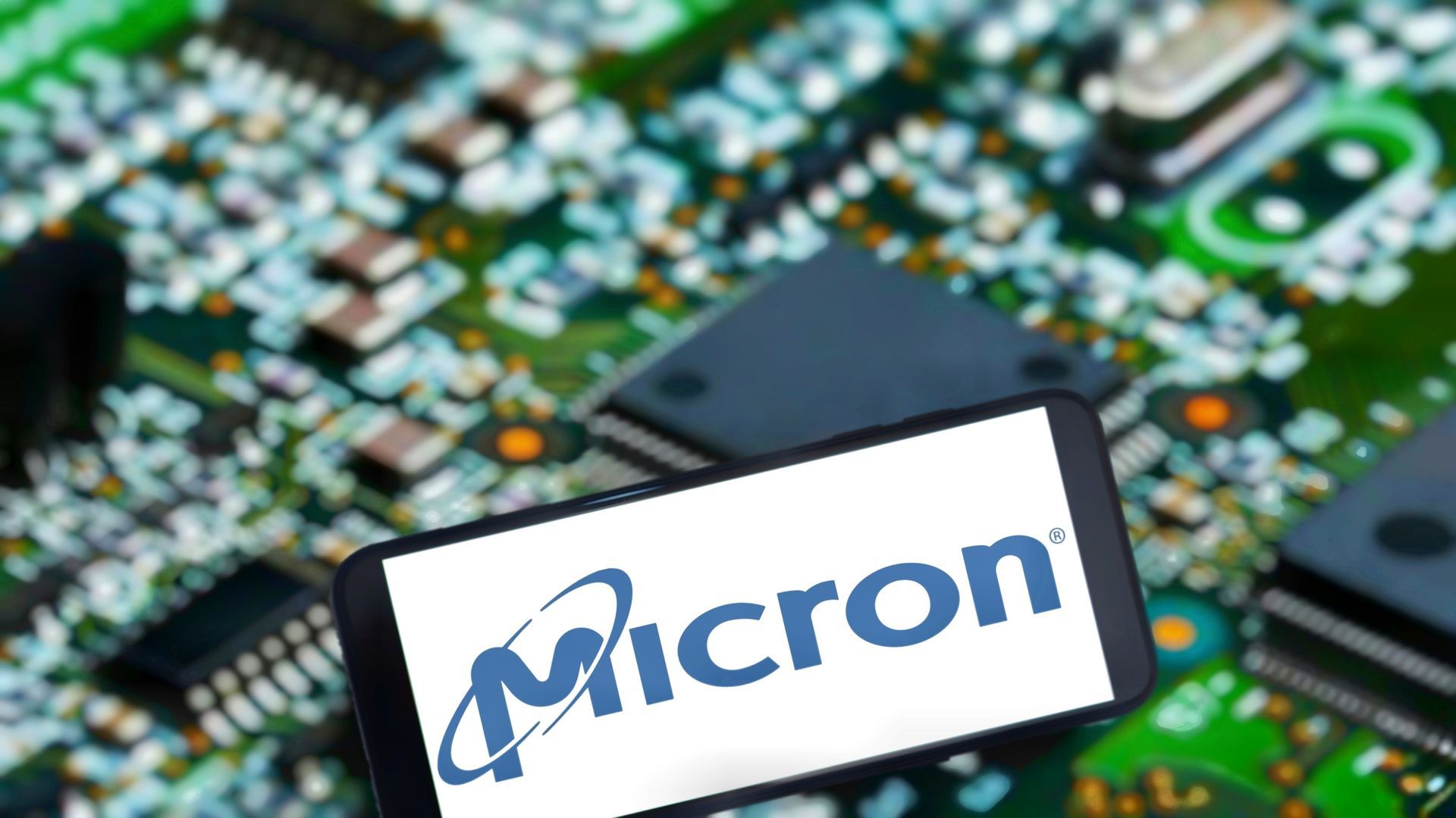 Smartphone displaying the Micron logo over a circuit board with microchips.