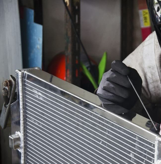 A Man Wearing Gloves is Working on a Radiator — Berrimah Radiator Service In Alice Springs, NT